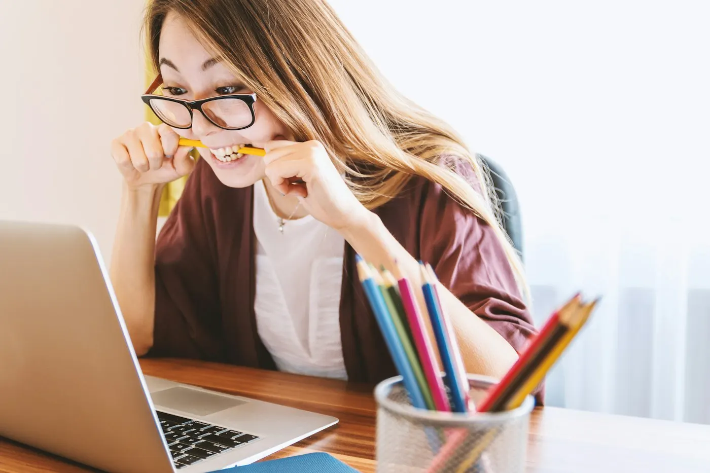 A student thinking at a desk with a laptop